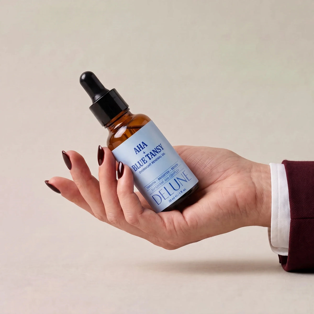 Delune AHA + Blue Tansy Overnight Renewal Oil held in an open hand