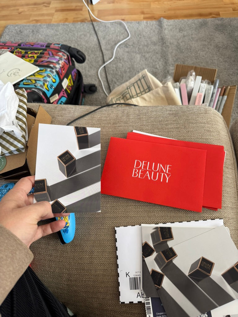 Printed Delune Beauty cards and red envelopes laid out for packing