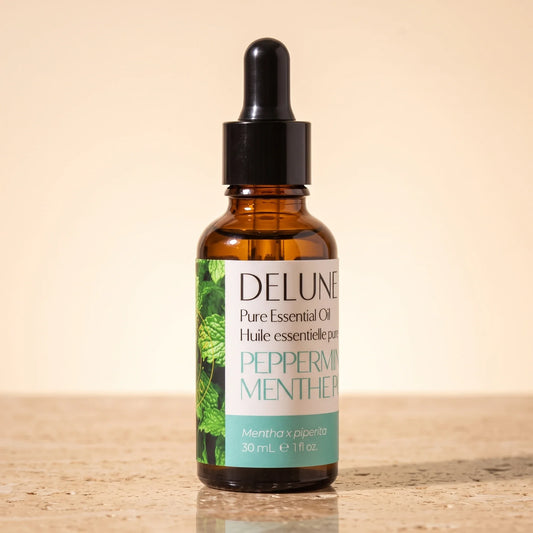 Delune Peppermint Pure Essential Oil, 30ml amber glass dropper bottle on warm travertine stone
