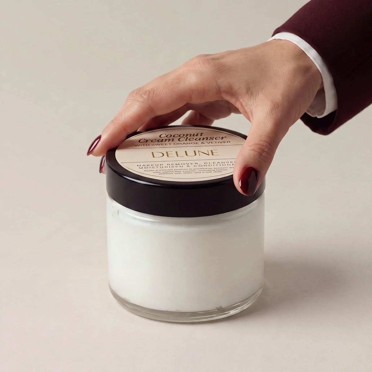Hand on the lid of Delune Coconut Cream Cleanser