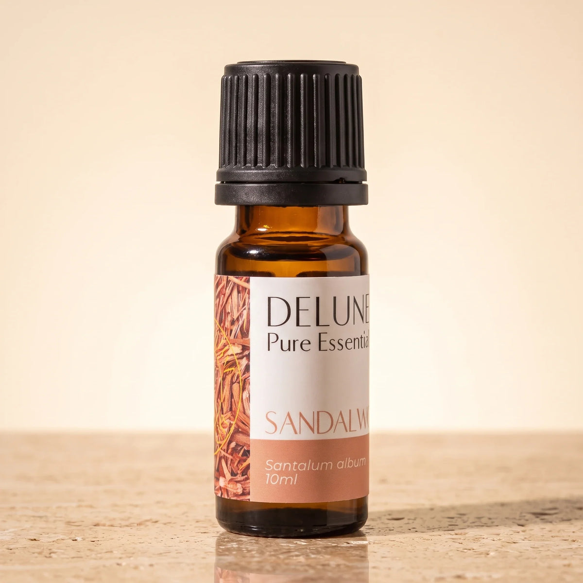 Delune Sandalwood Pure Essential Oil, 10ml amber glass bottle on warm travertine stone