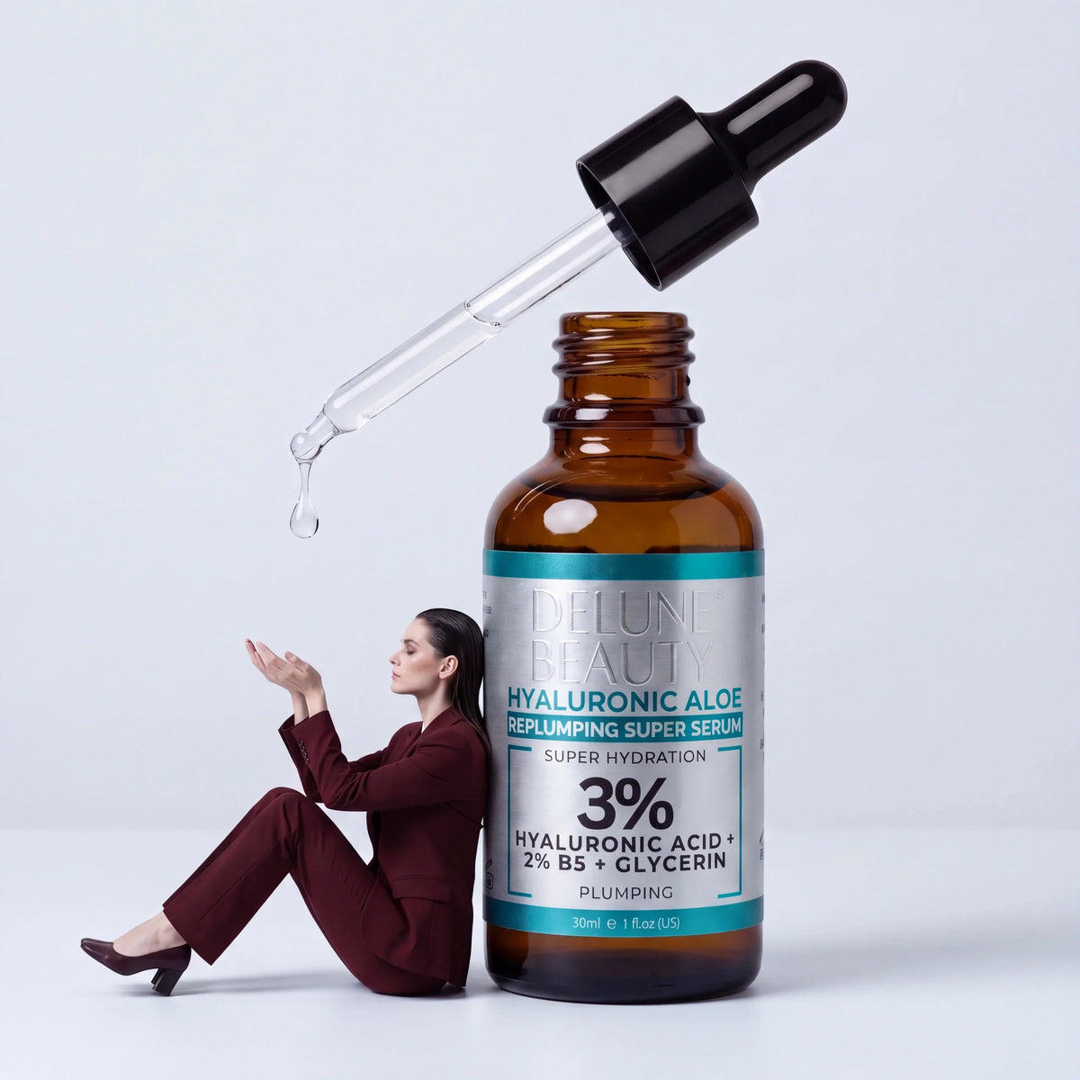 الترميم: امرأة ببدلة عنابية تستند إلى قارورة عملاقة من سيروم Hyaluronic Aloe وتلتقط قطرة